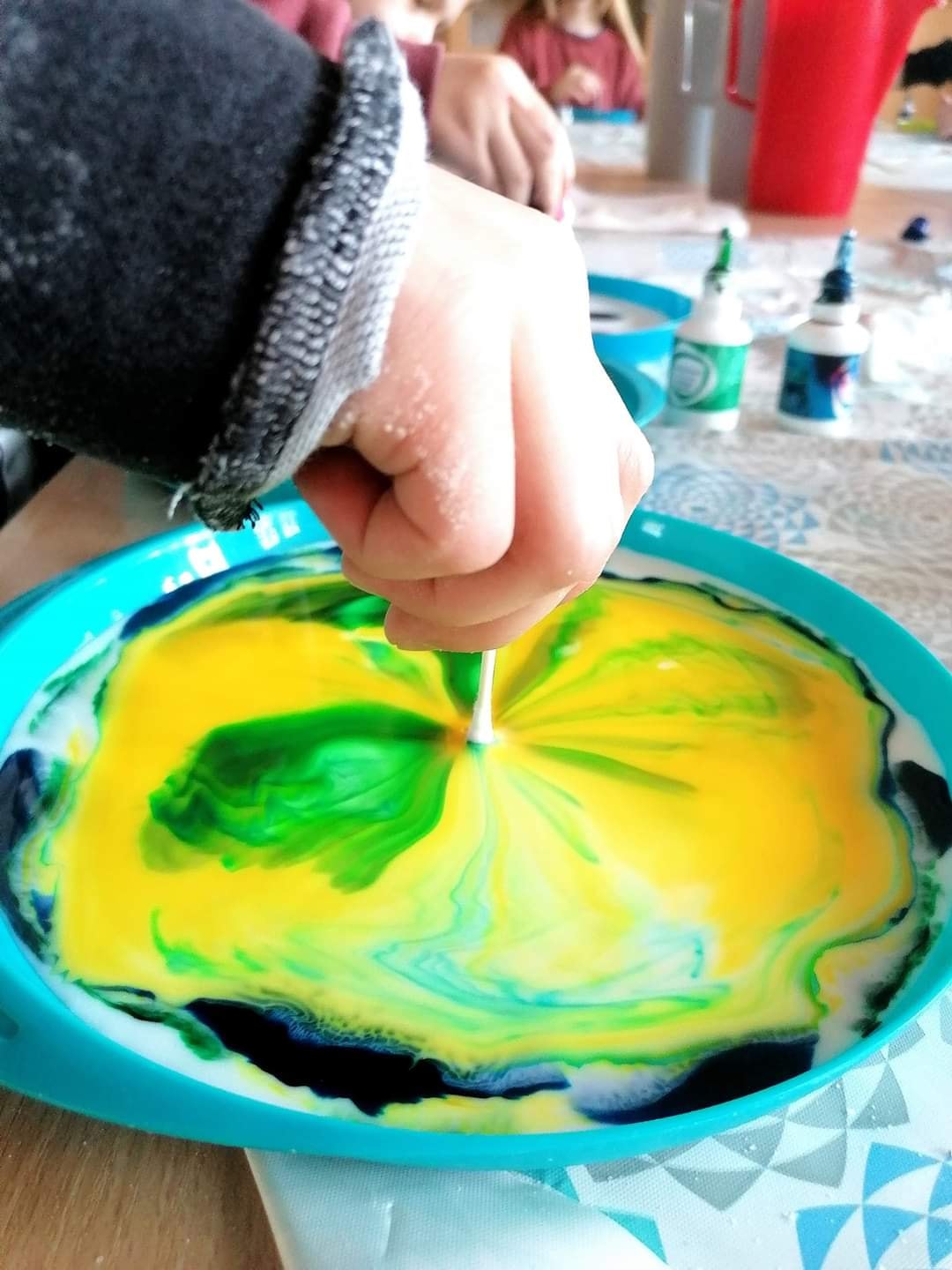 Dziecko wkłada patyczek higieniczny do mozaiki z farby