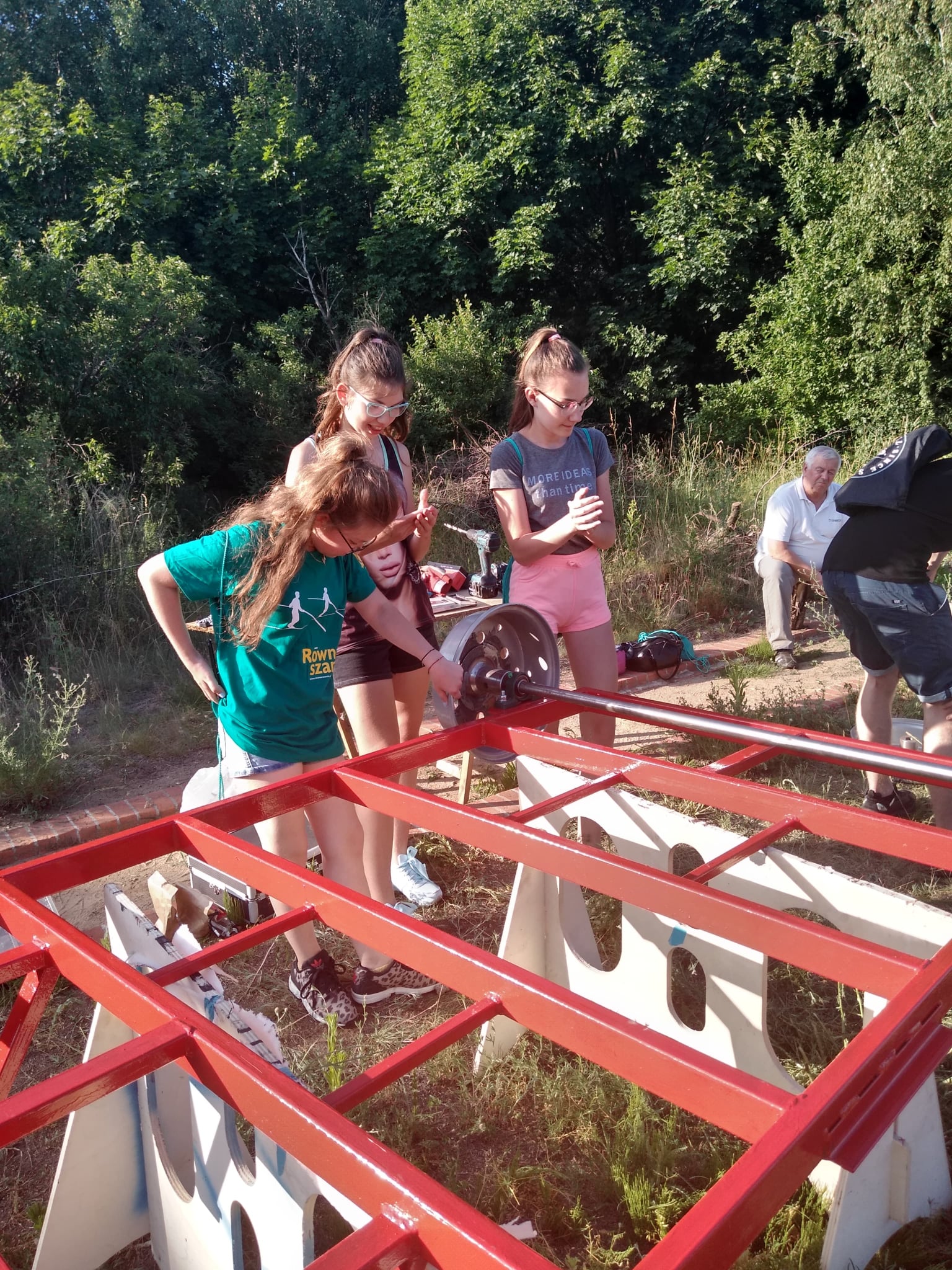Grupa dziewczynek pracująca nad projektem wózka szynowego.